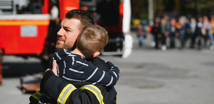 Portrait of rescued little boy with firefighter man standing near fire truck