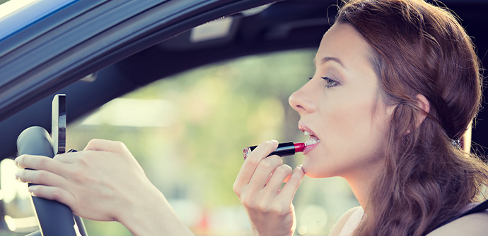 young woman applying makeup while driving car