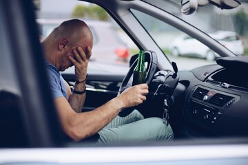 man driving a car with a beer in his hand