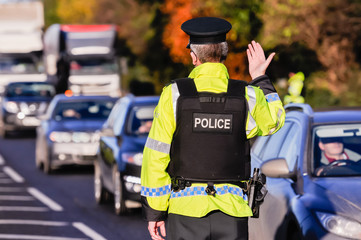 police motioning someone to stop at checkpoint