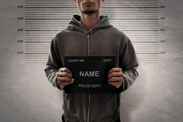 man holding plaque in front of mugshot wall